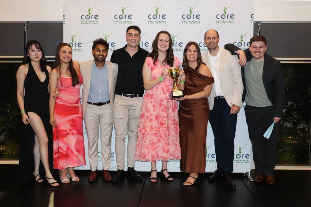 Group of people celebrating with a trophy at Core Physio & Pilates event.